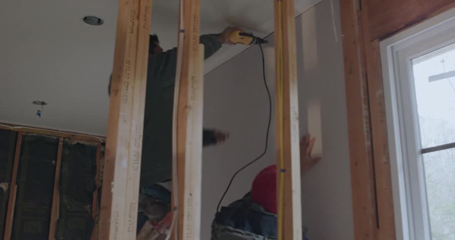 A construction worker is working inside a house in daylight