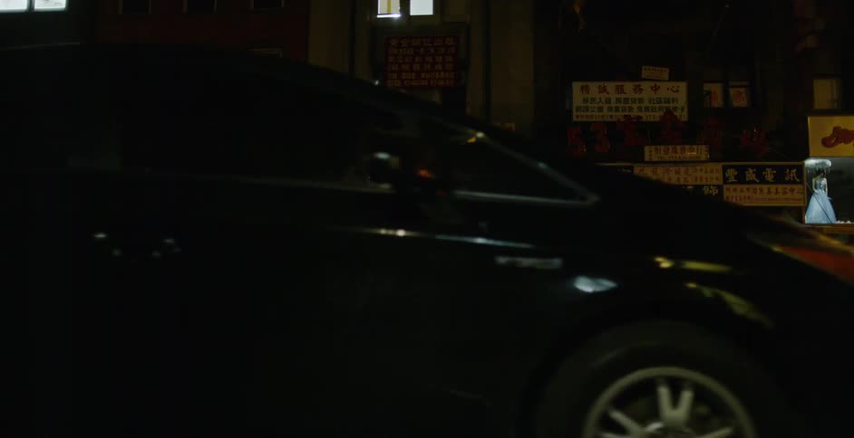 Lights on a sign illuminate a dark city road at night