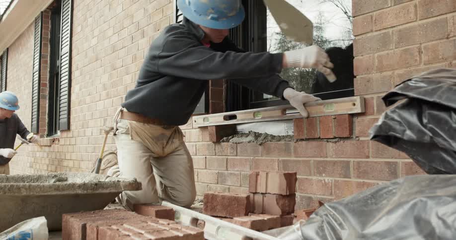 Construction worker lays brick on a windowsill