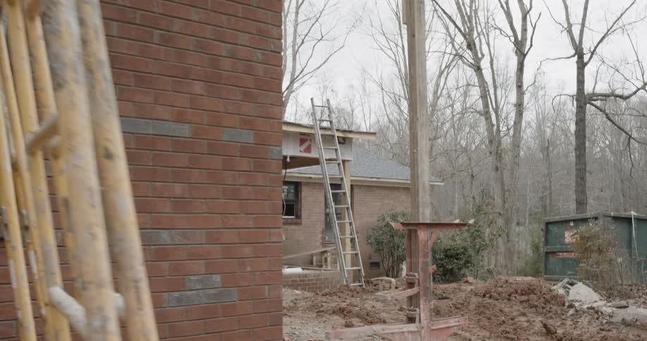 Construction equipment is set up outside of a brick house