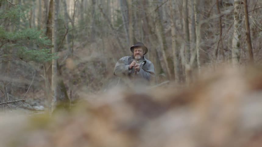 A confederate soldier is reloading his weapon while standing outside in daylight