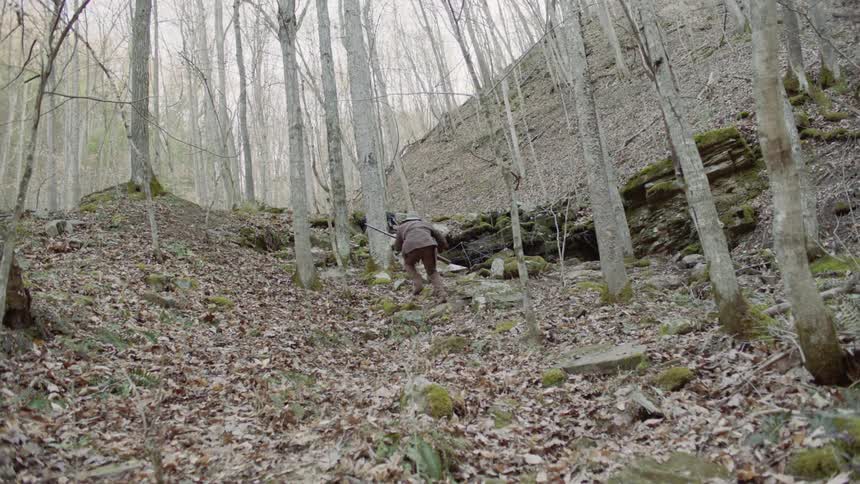 Two men run through the woods carrying rifles