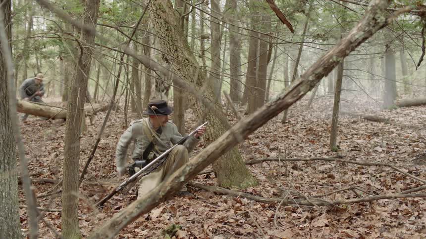 People firing, and loading rifles in the forest