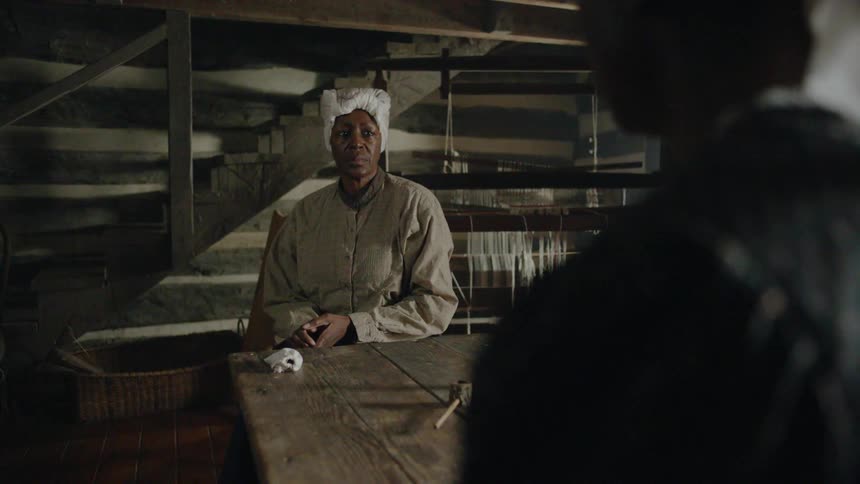 A woman pushes a pipe towards a man at a table