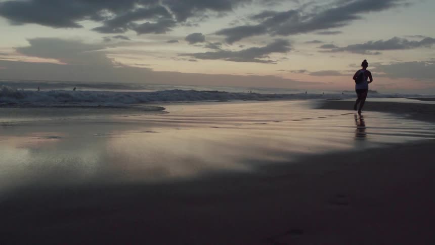 A girl runs along the beach at sunset