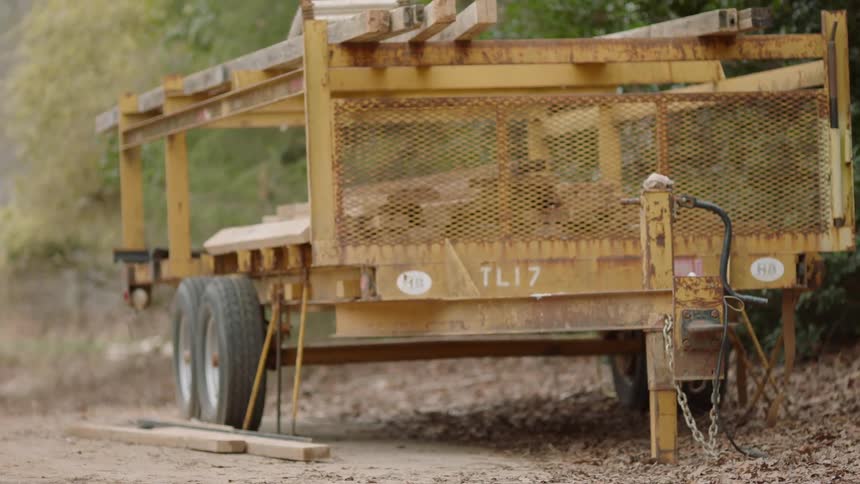 A construction trailer with lumber is parked in the dirt