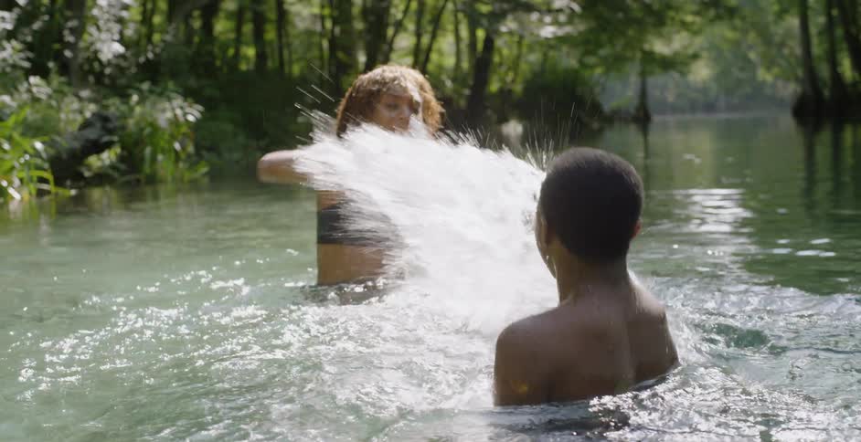 Woman splashes water on a child and gets splashed back in a lake