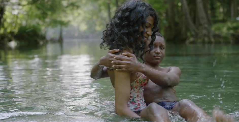 A woman helps a boy swim in a lake