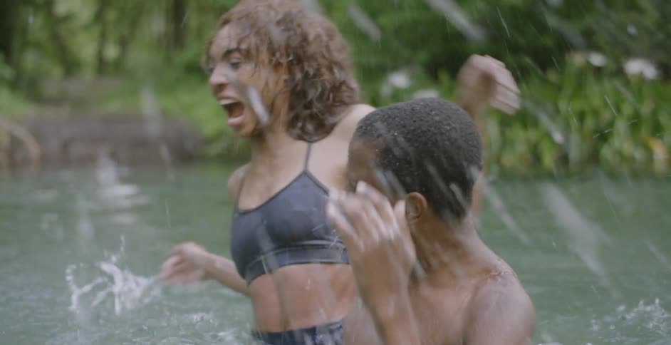 A woman splashes water on a young boy in the river