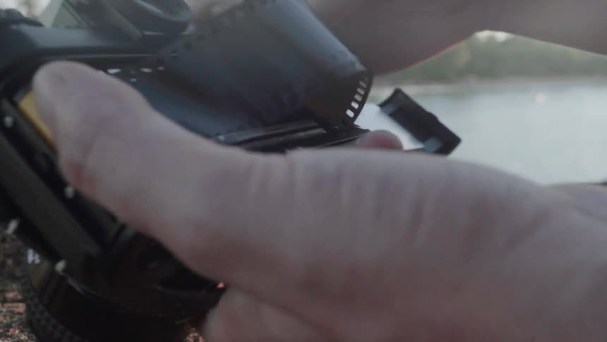 Person loading film in their camera on a cloudy day