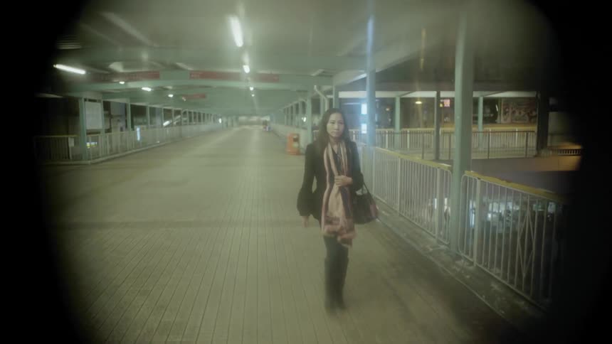 A woman walks down a bridge at night