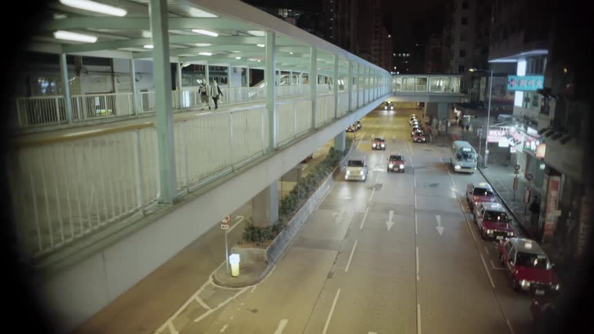 Two people walk on a bridge over a busy highway