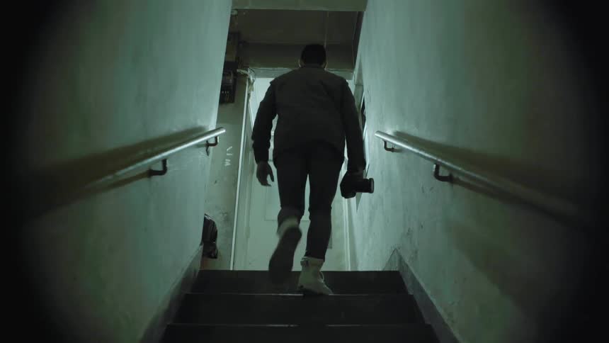 A man carries a camera up the stairs