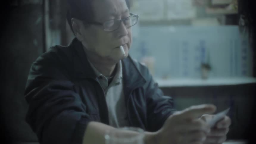 Man smoking a cigarette looks at playing cards and throws one on the table