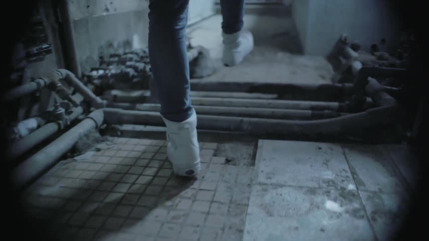 A person in white shoes walks down a corridor