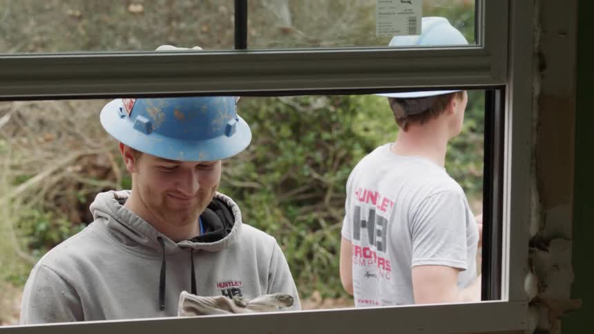 Workers stand outside a window talking
