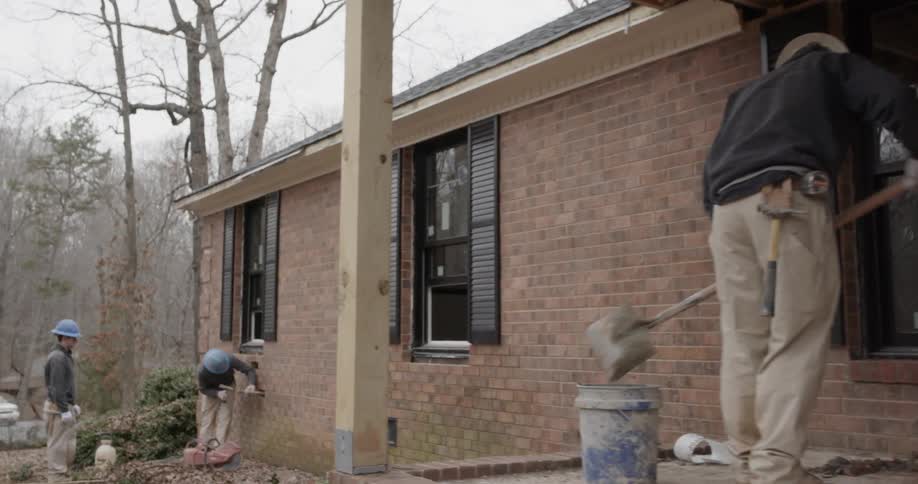 A construction worker cleans debris with a shovel