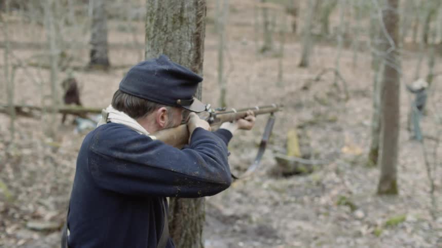 A civil war era soldier is shot at while hiding behind a tree