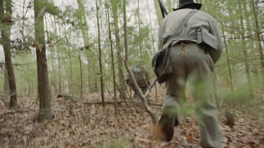 A man shoots a rifle in the woods