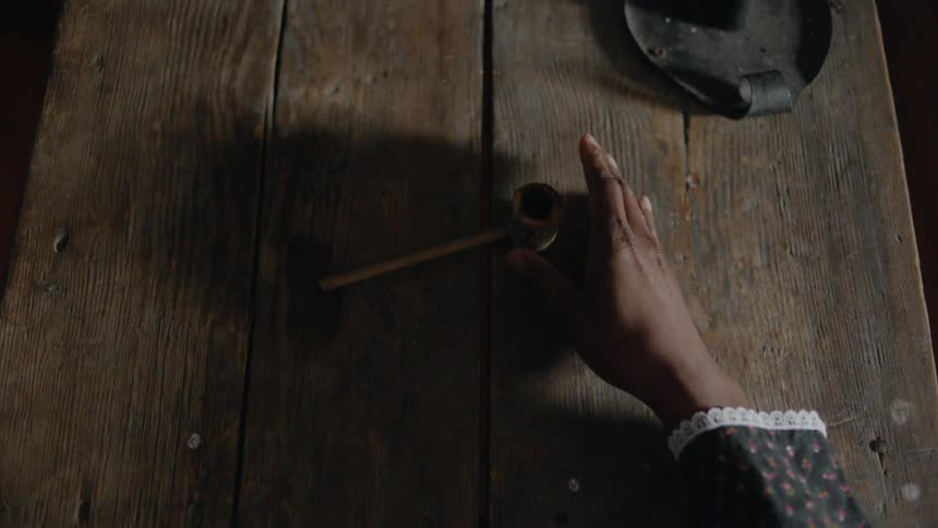 Hand picks up a pipe off a wooden table