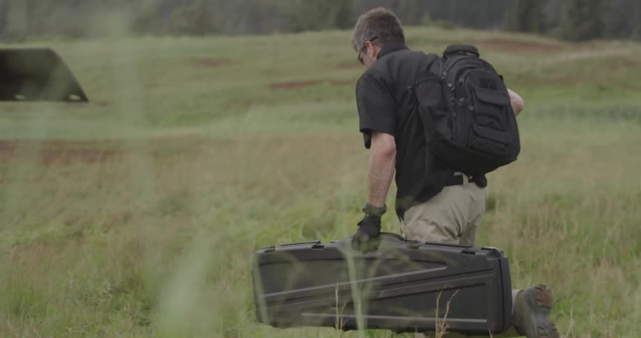 A man carries his rifle to a helicopter