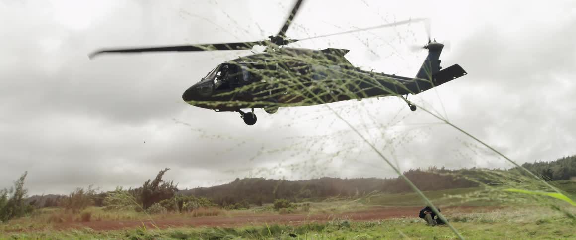 A large helicopter lifts off the ground into a cloudy sky