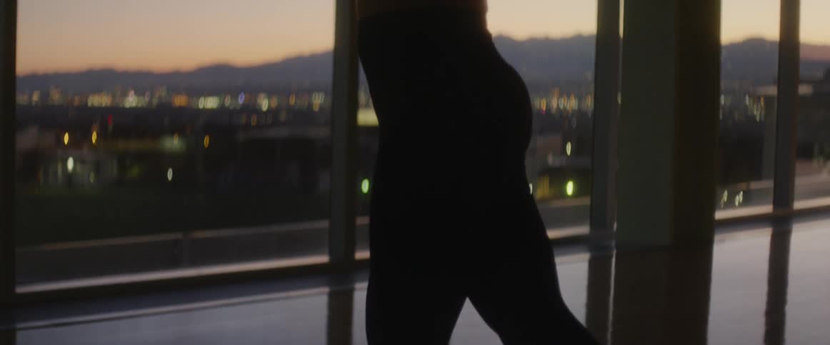 A man stretches in front of tall glass windows