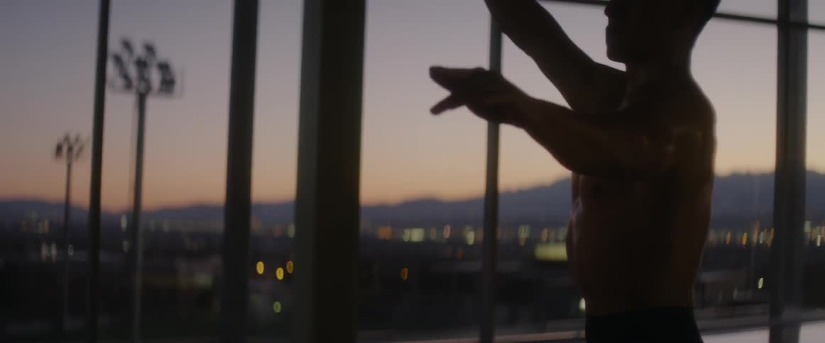 Man stands in building at dusk practicing dance moves