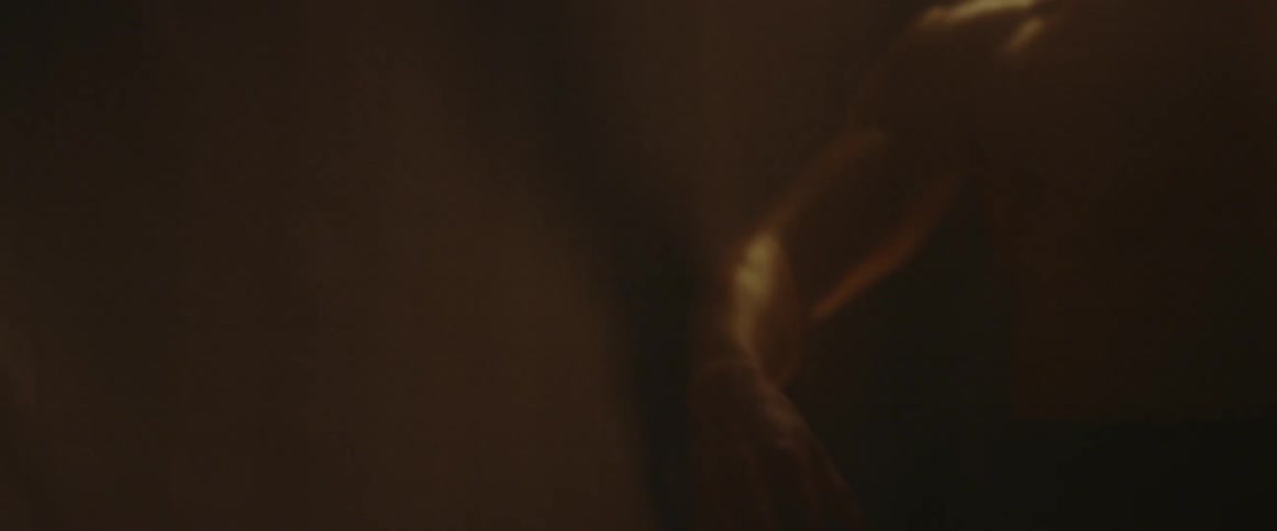 A shirtless man stretches and poses in hazy light