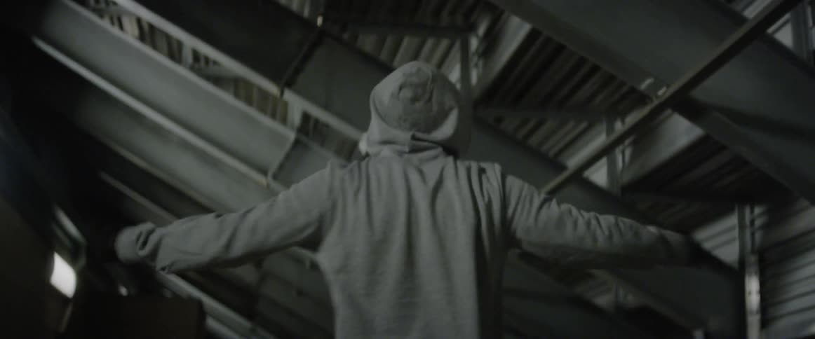 A male athlete is bouncing and warming up beneath a set of bleachers in daylight