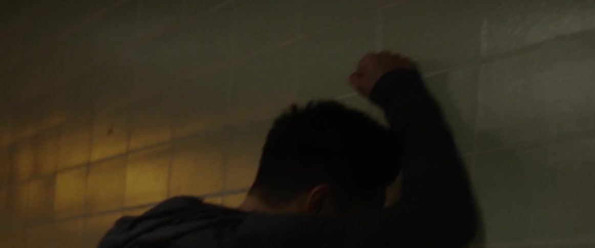 Jogging man stops and rests head against tile wall