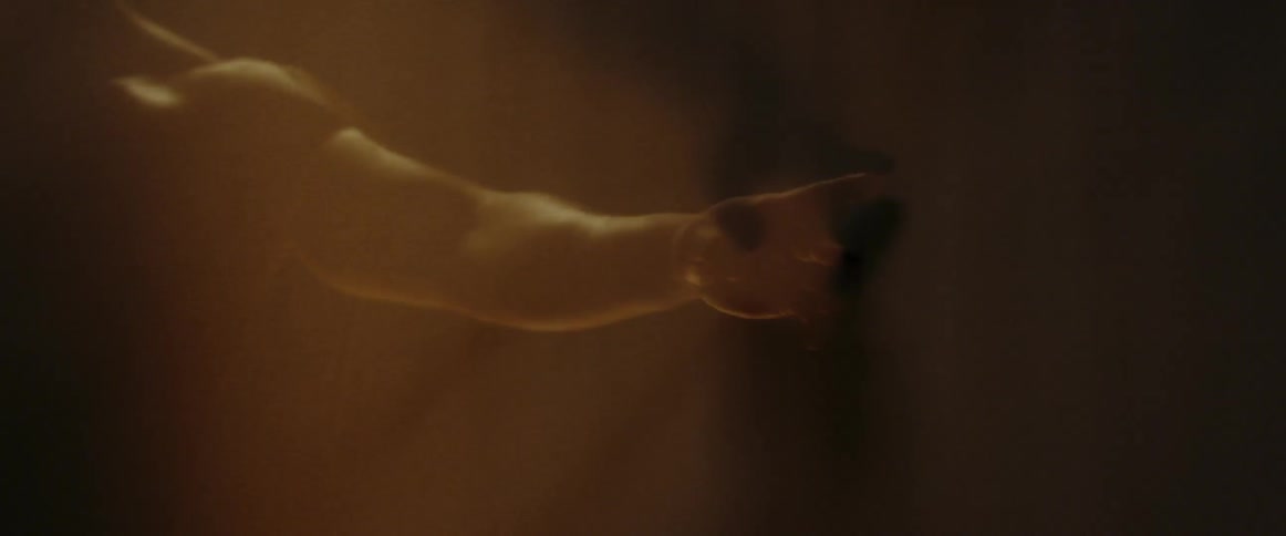 A man is waving his arms around in the dark room