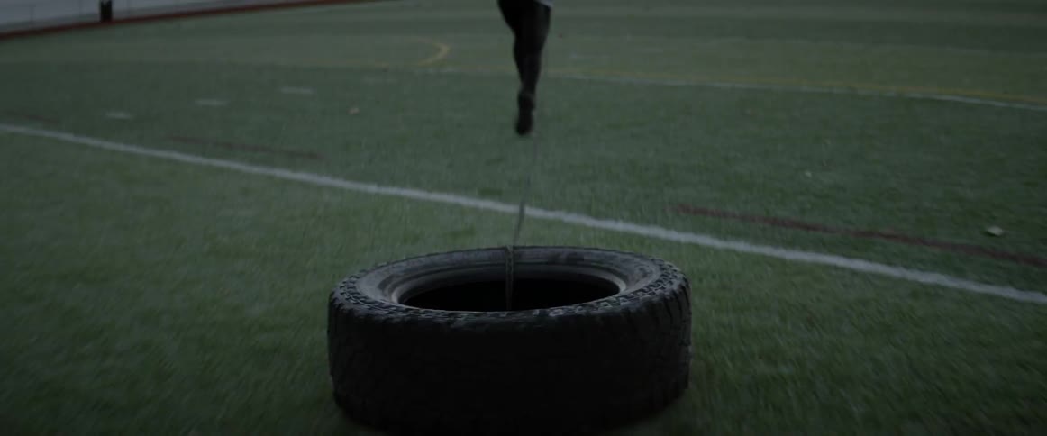 An athlete pulls a tire in an athletic field