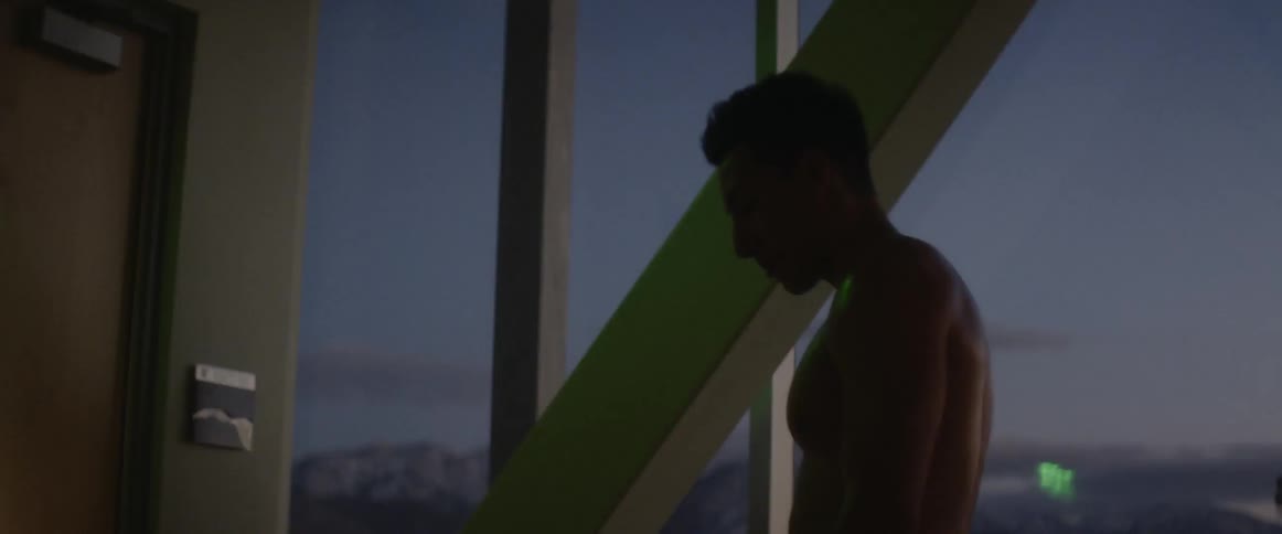 Man stands in room at night, flexing his shoulders