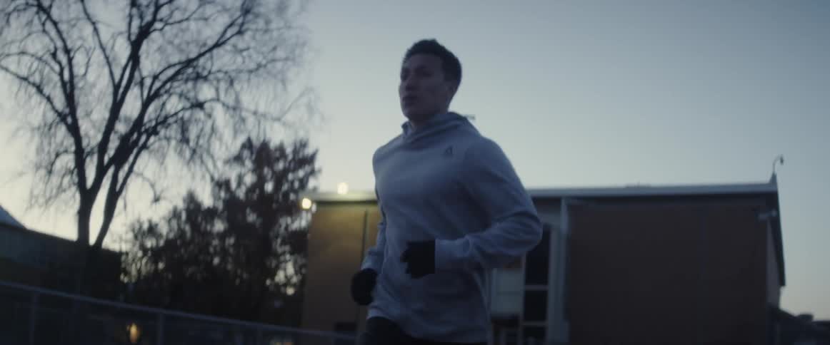 A man is jogging at sunset past the building