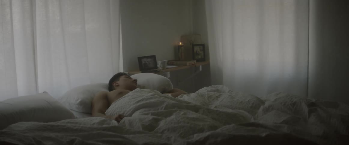 A man is sleeping in a bed early in the morning