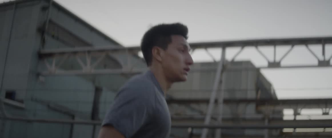 Man jogs by concrete building at sunset