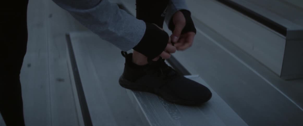 A man ties his shoes on the bleachers