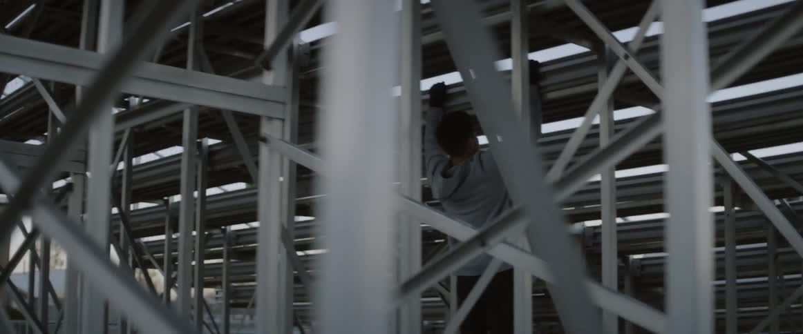 A man does pull ups below a set of bleachers