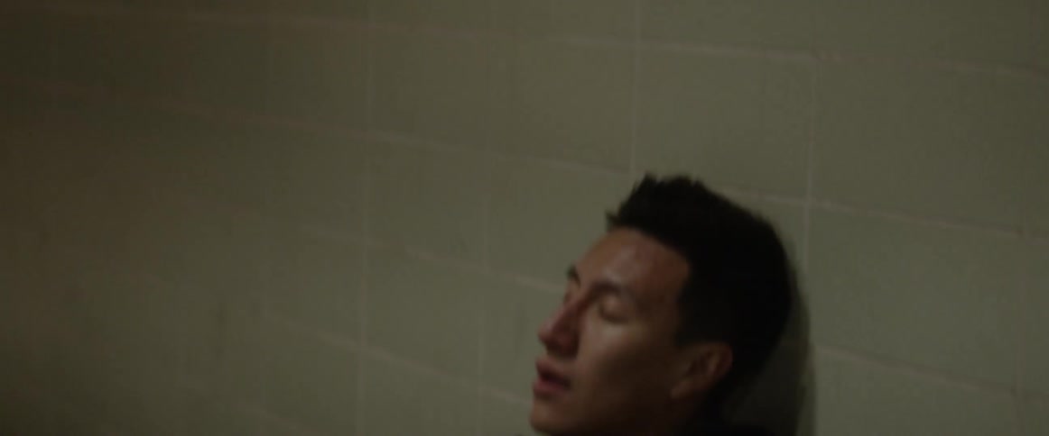Man breathes heavily while leaning against a wall
