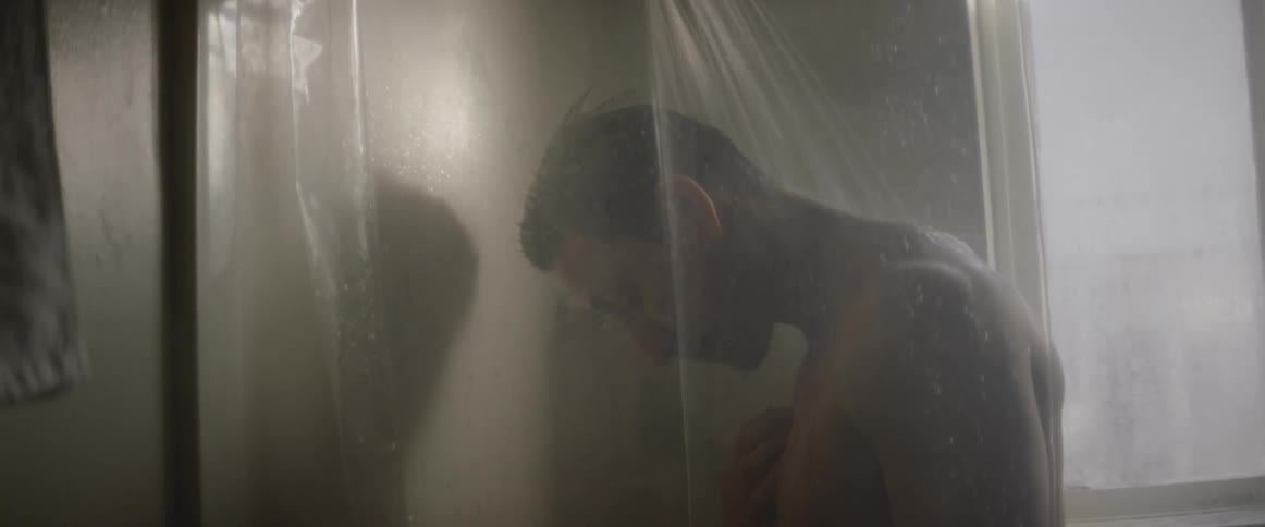 A man is showering in the dark bathroom