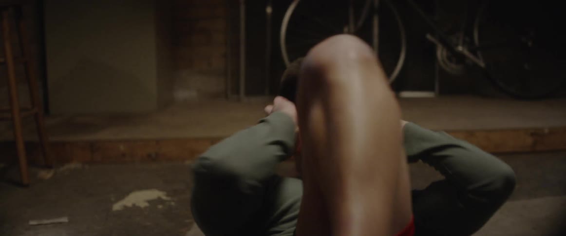 A male athlete is doing crunches on the ground in daylight