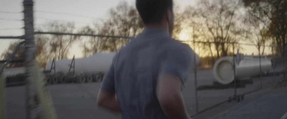 A man is jogging outside past the fence