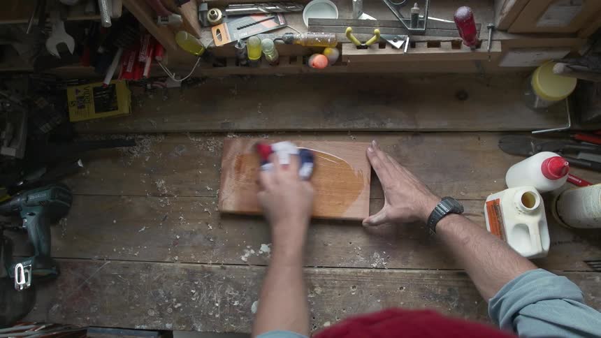 A man is using oil to stain wood
