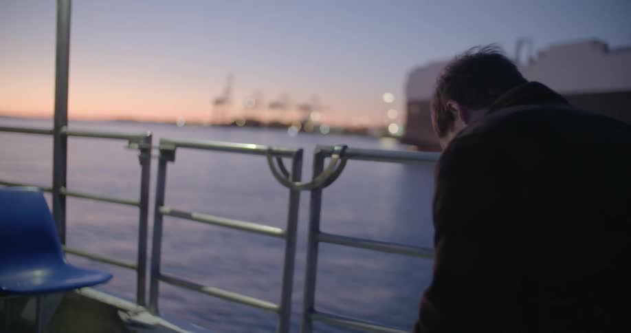 A man rides a ferry at sunset