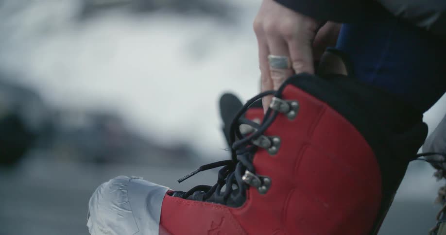 A man tucking his pant legs into ski boots and lacing the boots
