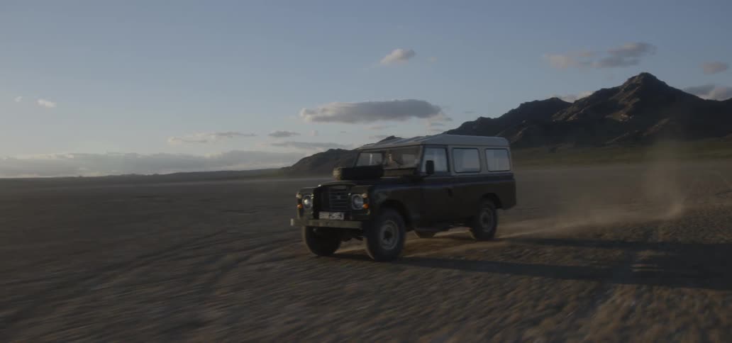 The truck drives fast over the desert on a sunny day