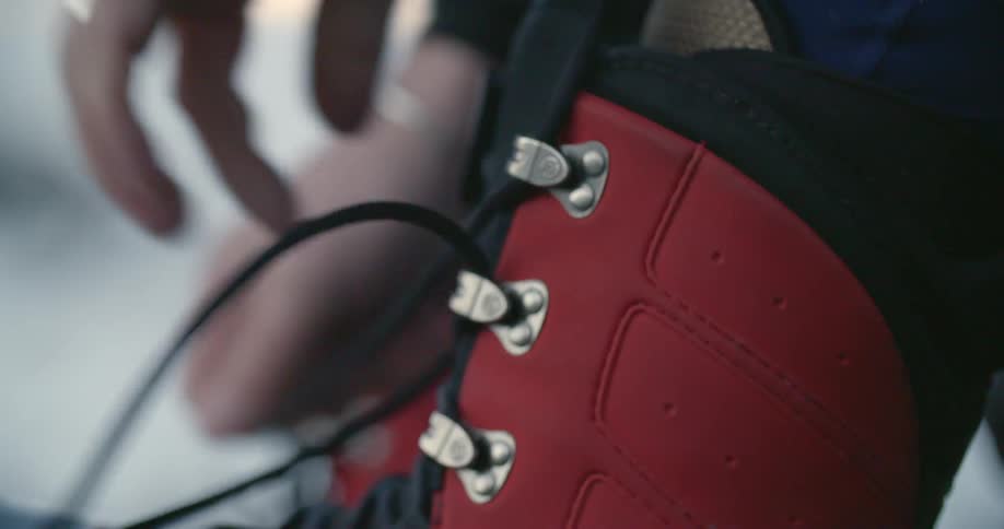 A person laces up red boots