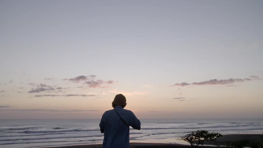 Man taking pictures on the beach at sunset