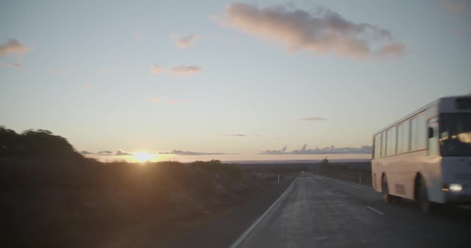 Vehicles driving on a rural road at sunset